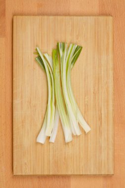 Tahta bir kesme tahtasının üzerinde dilimlenmiş yeşil soğan.