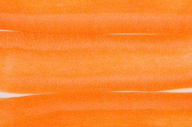 Yakın çekim, yukarıdan aşağıya bakış, ince dilimlenmiş havuçları gösteriyor. Paralel çizgiler halinde düzenlenmiş, canlı turuncu renklerini ve hassas dokularını gösteriyor.