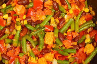 Yeşil fasulye, mısır, fasulye ve kırmızı biber içeren pişirilmiş sebze karışımının yakın plan çekimi.