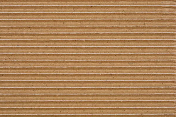 Yakın çekim, yatay oyuklar ve küçük beyaz kağıt yırtıkları ile kıvrımlı karton dokuyu yakalar ve katmanlı yapısını ortaya çıkarır.