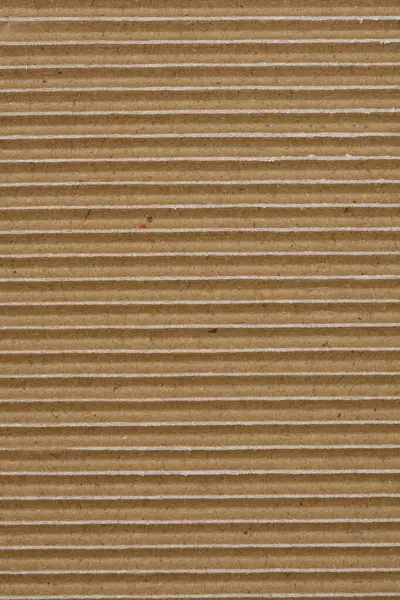 Yakın çekim, yatay oyuklar ve küçük beyaz kağıt yırtıkları ile kıvrımlı karton dokuyu yakalar ve katmanlı yapısını ortaya çıkarır.