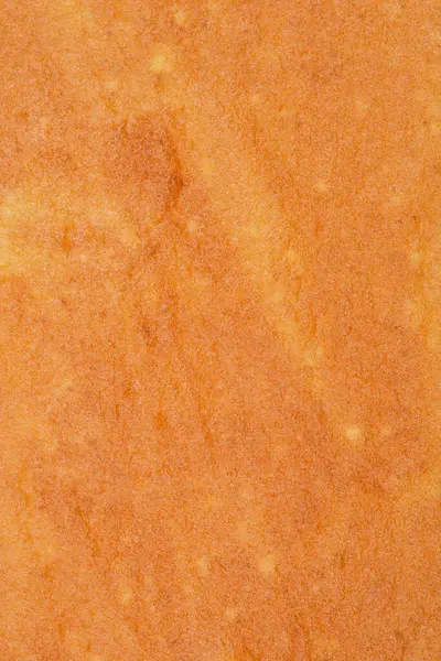 Fırında pişmiş bir kek katmanının yakın çekim, dokulu bir yüzeyi, sıcak, altın-kahverengi rengini ve narin desenlerini sergiliyor, rulo kek tabanı için mükemmel.