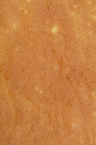 Fırında pişmiş bir kek katmanının yakın çekim, dokulu bir yüzeyi, sıcak, altın-kahverengi rengini ve narin desenlerini sergiliyor, rulo kek tabanı için mükemmel.