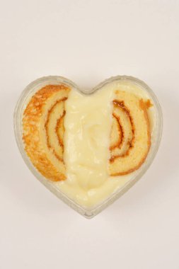 Yukardan çekilmiş, kalp şeklinde bir cam kase ve vanilyalı krema.