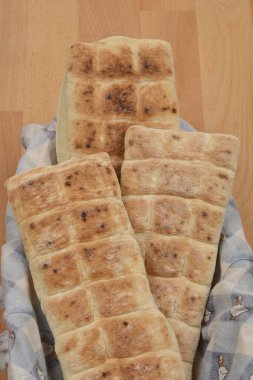 Mutfak havlusuyla sepette üç parça ekmek, yakından çekilmiş.