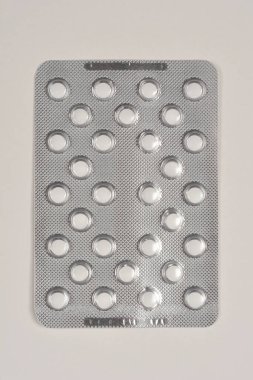 Beyaz, yuvarlak haplardan oluşan bir paketin yakın plan çekimi folyo ambalajının içindeki doku ve düzenlemeyi gösteriyor.