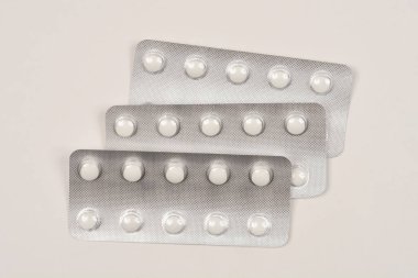 Arka planda beyaz yuvarlak haplarla dolu üç alüminyum su toplayıcısının yakın plan çekimi.