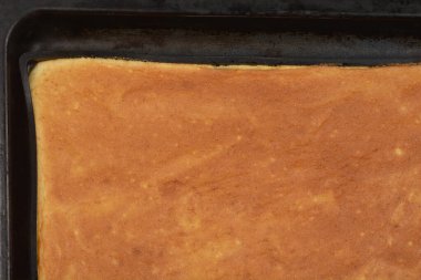 Yeni pişmiş altın sarısı bir sünger keki siyah bir tavada.