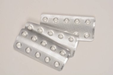 Arka planda beyaz yuvarlak haplarla dolu üç alüminyum su toplayıcısının yakın plan çekimi.