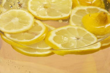 Birkaç limon dilimi cam bir kabın içinde berrak suya batırılır.