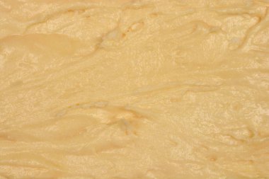 Yakın çekim, pişmemiş sarı limonlu kek hamurunun dokulu yüzeyini gösteriyor.