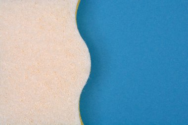 Dalgalı kenarı olan desenli beyaz bir sünger kısmen koyu mavi arkaplana karşı gösterilir