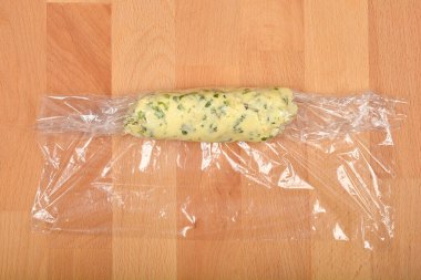 Yukardan aşağı doğru çekimde, tereyağı kütüğünün tahta bir yüzeye sarılı naylon ambalaja sarılı olduğu görülüyor.