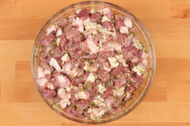 Doğranmış ve sosis yapımına hazır domuz eti, ahşap bir arka planda yuvarlak cam bir kasede sunuluyor.