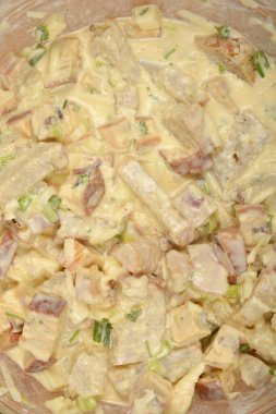 Yukardan aşağıya doğru sıkıca kırpılmış bir görüntü, temiz bir kasede kremalı ekmek, sebze ve peynir karışımını gösteriyor.