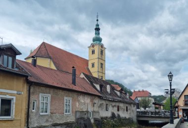 Samobor 'da bulutlu bir günde, St. Anastasia Kilisesi' nin çan kulesi su yolu boyunca kırmızı kiremitli çatıları olan büyüleyici eski binaların üzerinde yükseliyor.