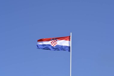 Kırmızı, beyaz ve mavi yatay çizgiler ve kareli armanın yer aldığı Hırvat ulusal bayrağı, açık mavi gökyüzüne hafifçe el sallıyor