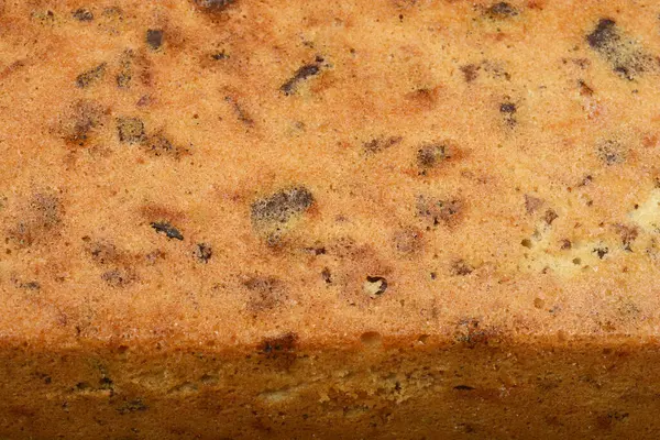 Cevizli, kuru üzümlü, çikolatalı ve portakal aromalı yeni pişmiş bir ekmeğin dokulu yüzeyi.