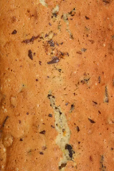 Cevizli, kuru üzümlü, çikolatalı ve portakal aromalı yeni pişmiş bir ekmeğin dokulu yüzeyi.