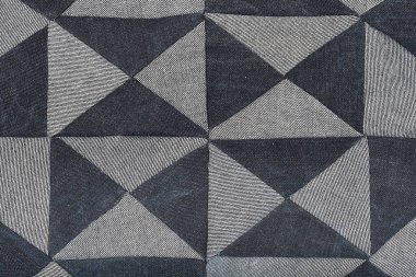 Açık ve koyu mavi kot parçalarından oluşan desenli bir yama geometrik elmas ve üçgen deseni oluşturur.