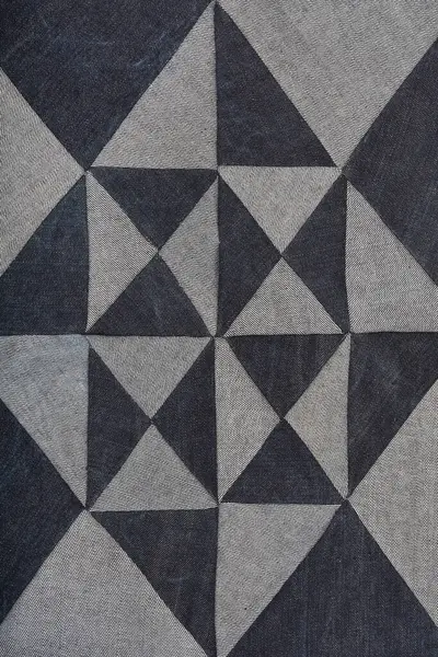 Açık ve koyu mavi kot parçalarından oluşan desenli bir yama geometrik elmas ve üçgen deseni oluşturur.