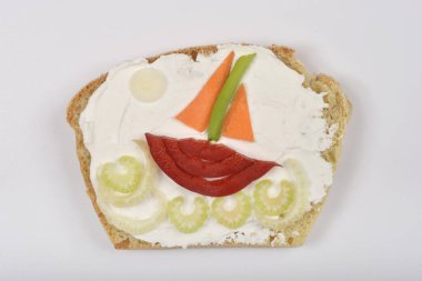 Beyaz arka planda krem peynirli ve sebzeli sandviç. Dalgalardaki bir tekneye benziyor.