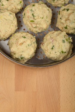 Tahta bir yüzey üzerinde pişirilmeye hazır metal bir buhar tenceresine konmuş otlu ekmek hamuru.