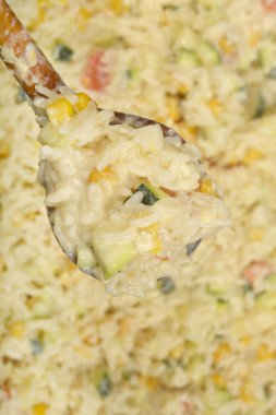 İçinde kabak, mısır ve kırmızı biber bulunan ahşap kaşıklı kremalı sebzeli risotto.