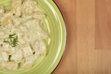 Bu resim, ahşap bir yüzeyde yeşil bir tabakta servis edilen kremalı gorgonzola soslu ev yapımı gnocchi 'yi gösteriyor.