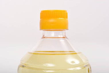 Açık sarı bir kapaklı, şeffaf plastik bir şişe. Açık sarı bir arkaplan üzerine kurulmuş.