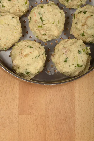 Tahta bir yüzey üzerinde pişirilmeye hazır metal bir buhar tenceresine konmuş otlu ekmek hamuru.