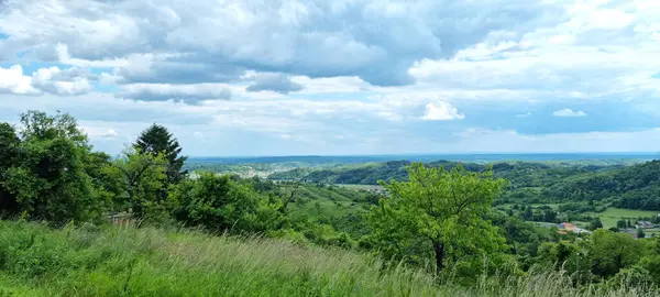 Gornje Psarthe 'nin panoramik manzarası güneybatı vitrinlerini gösteriyor. Yeşil tepeler, yemyeşil ağaçlar ve bulutlu bir gökyüzünün altındaki uzak köyler.