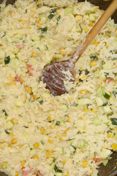 İçinde kabak, mısır ve kırmızı biber bulunan ahşap kaşıklı kremalı sebzeli risotto.
