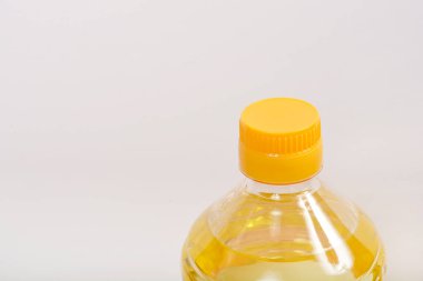 Açık sarı bir kapaklı, şeffaf plastik bir şişe. Açık sarı bir arkaplan üzerine kurulmuş.