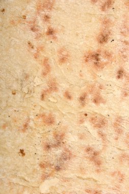 Yakın çekim, yukarıdan aşağı görüntü düz ekmeğin dokusunu, hafifçe kahverengileşmiş altını gözler önüne serer