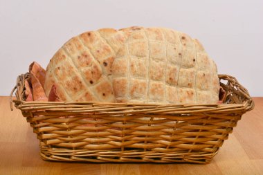 Yuvarlak düz ekmekler hasır bir sepetin içinde kareli bir bezle ahşap bir masanın üzerinde otururlar.