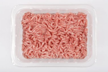 Tepeden çekimde, tarafsız bir arkaplanda içi çiğ, açık pembe et dolu şeffaf bir plastik tepsi görülüyor.