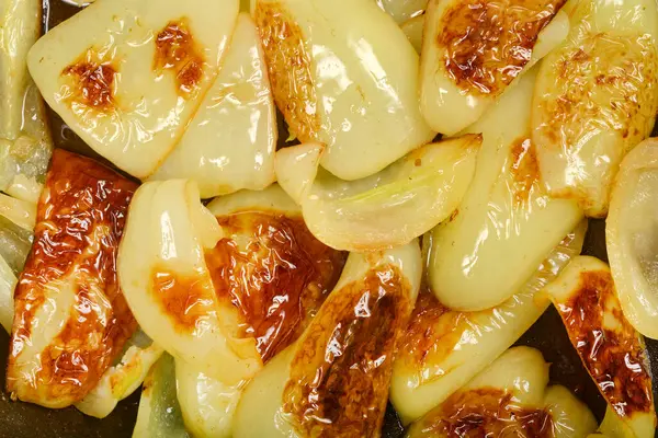 Yakın plan, tepeden çekimde açık yeşil dolma biber dilimleriyle dolu bir tava görülüyor. Bunların çoğu pişirmekten çok güzel kahverengiye boyanmış.