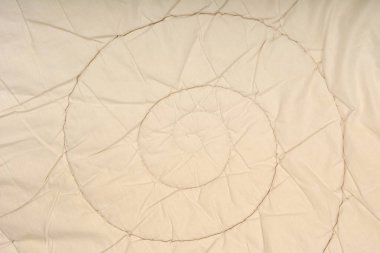 Sarmal dikiş desenli bej bir yorganın yakın plan çekimi.