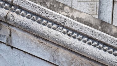 Bu yakın plan görüntüde eski, yıpranmış bir taş balya ya ya da korkuluklardan oluşan oyulmuş piramit ya da elmas şekilleri var. Yaş ve doku yüzeylerini gösteriyor.