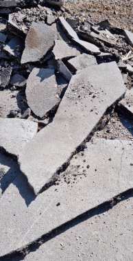 Kırık asfalt ve beton döşemeler yere saçılmış. Bu da bir inşaat ya da yıkım alanı olduğunu gösteriyor.