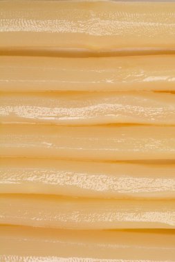 Yakın plan dikey çekim, yatay olarak sıralanmış pişmiş beyaz kuşkonmaz mızraklarının pürüzsüz, soluk yüzeyinin ayrıntılı bir görüntüsünü sağlar.