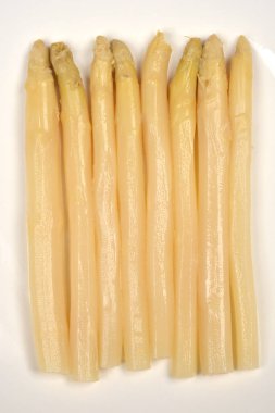 Yakın çekim, yukarıdan aşağıya doğru birkaç pişmiş beyaz kuşkonmaz mızrağını düz beyaz bir tabakta düzgünce dizilmiş olarak gösteriyor.