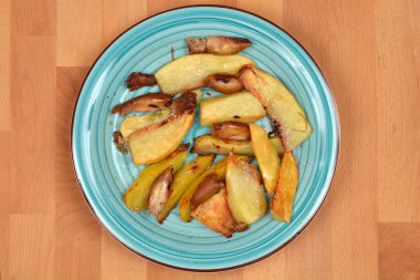 Mavi tabakta kızarmış patates dilimleri ve ahşap bir masaya doldurulmuş mürekkep balığı var.