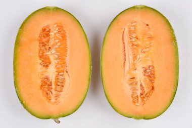 Olgun kavunun iki yarısı, canlı portakal eti ve bol miktarda tohum sergilenir, beyaz bir arka planda yatay olarak sergilenir.