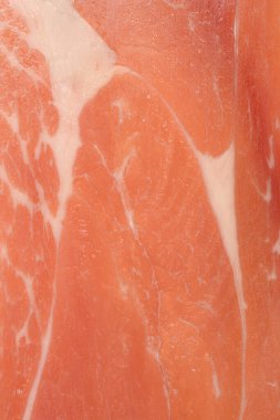 Yakın çekim, yukarıdan aşağı görüntü ince dilimlenmiş prosciutto 'nun karmaşık dokusunu ve mermerini yakalar ve tüm çerçeveyi doldurur.