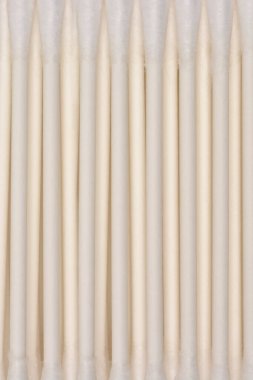 Bu yakın plan görüntü beyaz bir yüzeyde yatay olarak sıralanmış açık renkli pamuklu çubukları gösteriyor.