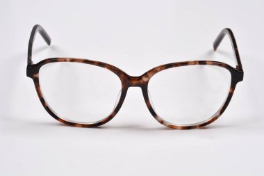 Açık mercekli bir çift şık kaplumbağa desenli gözlük düz beyaz arka planda belirgin bir şekilde sergilenir