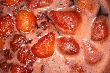 Çilek kaynayan ve kaynayan bir tencerede yakın çekim, reçel yapma işlemi sırasında zengin dokuyu ve canlı kırmızı rengi yakalamak