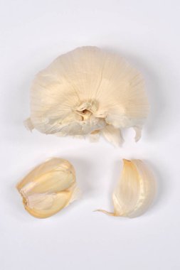 G sarımsak soğanı, karanfillerden ayrılmış, sade beyaz bir arkaplan üzerine yerleştirilmiş.